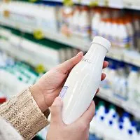 Beleucht Milchbereich im Supermarkt Person hält Milchflasche im Supermarkt fest